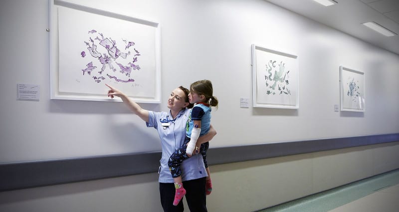 A young patient in the arms of a nurse looking at Life Under Water 4, 5 and 6 by Quentin Blake. Part of the Paintings in Hospitals collection.